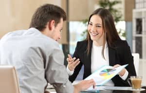 A smiling counselor shows a client a paper with a chart