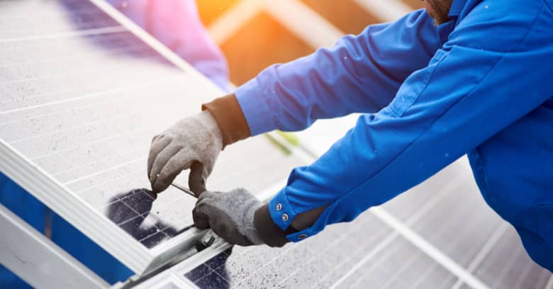 A worker installs solar panels on a building