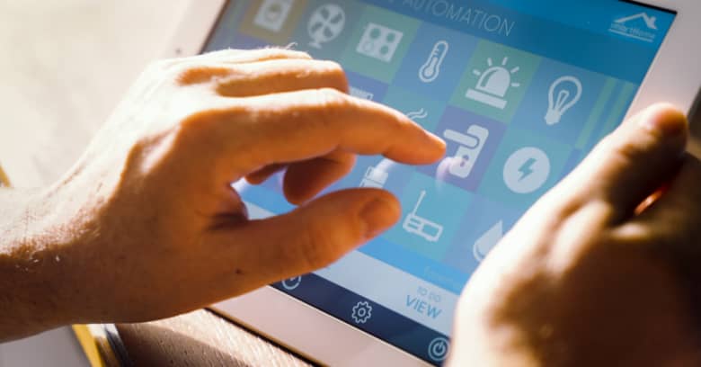 A man is seen operating his home's environmental controls via a computer tablet