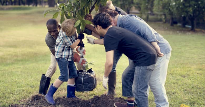 A diverse group of people plant a tree