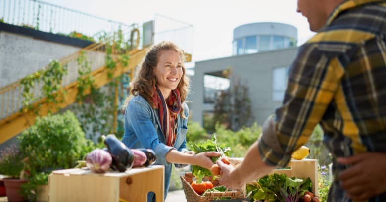 A man shops for produce at his local farmer's market while a local grower helps him