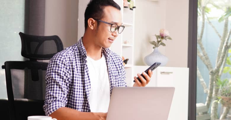 A man uses his computer and smartphone to shop for insurance quotes