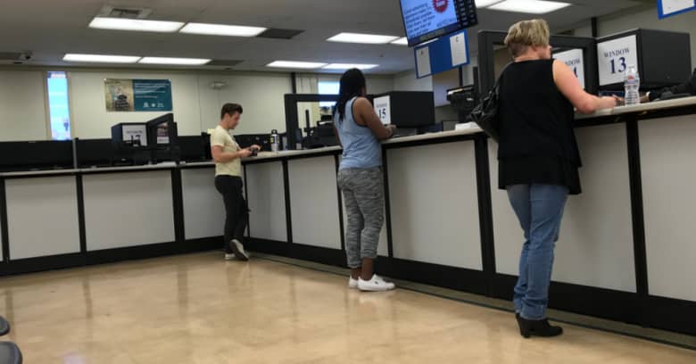 People are shown conducting business at their local DMV