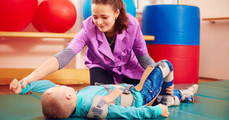 A physical therapist works with a boy who has disabilities.