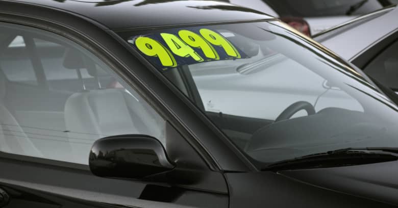 A used black car is shown with a sales sticker on it