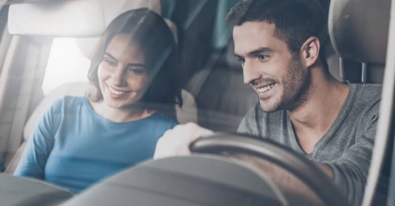 a young man prepares to test drive a new car while his girlfriend sits in the passenger seat