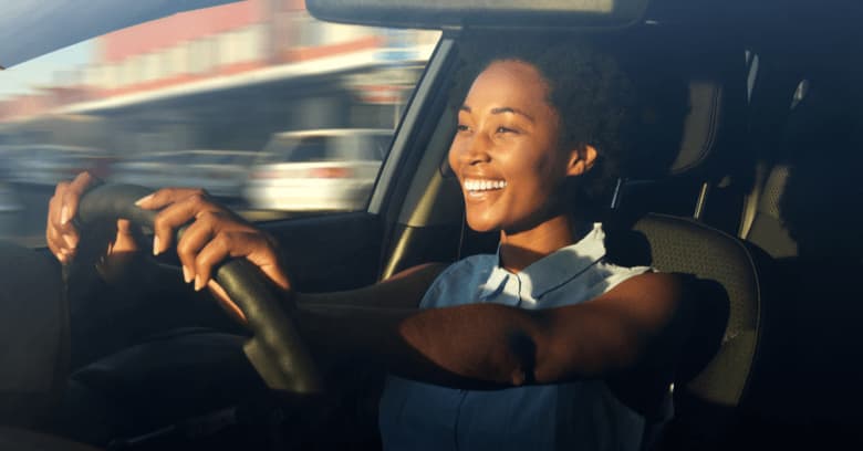 A young woman is happy to be driving her new car.