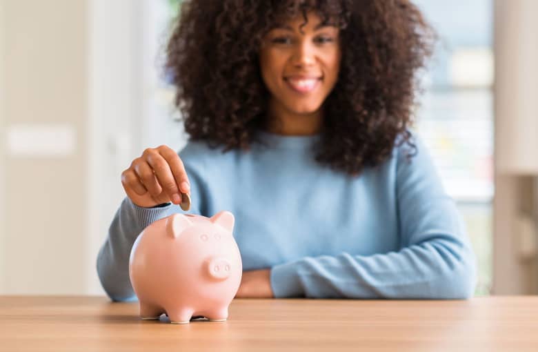 A woman drops coins into a piggy bank