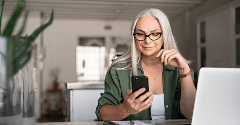 A woman looks at phone and smiles to see that she's been given a car insurance rebate