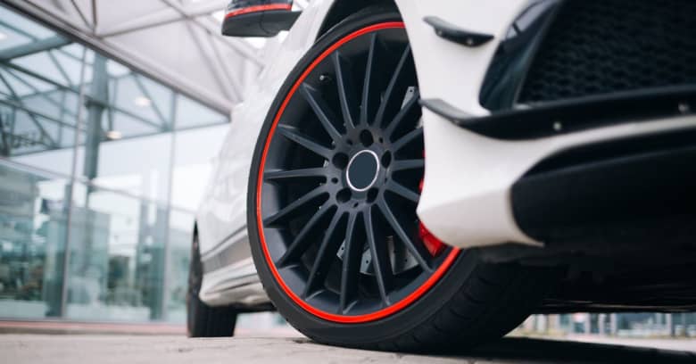 A white car with nice red and black rims.