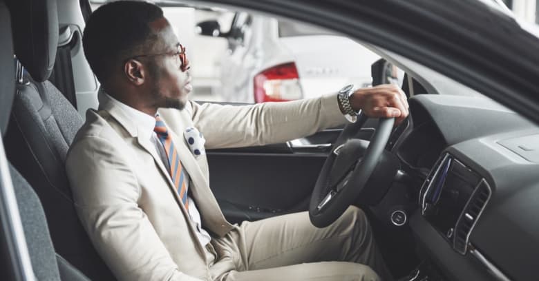 A young man is driving a rental car while his personal car is in a repair shop.