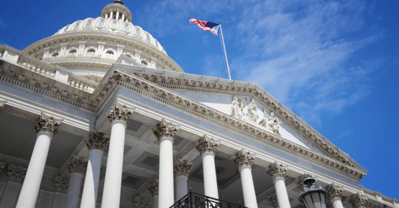 The US Congress Building is viewed from a low spot, and the U.S. flag is flying from the building