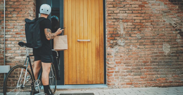 a bicycle courier is seen delivering food to a home.