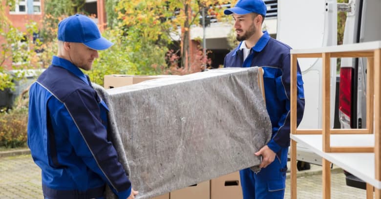 Two men, who are professional movers, move items into a new home