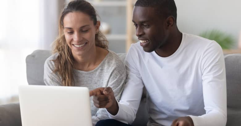 A couple sit in front of a computer discussing their household finances.