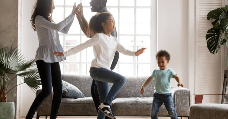 a family enjoys dancing together in their living room as they stay inside during the coronavirus quarantine