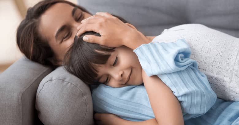 A little girl and her mother hug each other tightly with smiles on their faces.