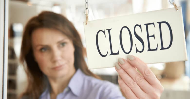 a woman puts a 'closed' sign up at her place of business