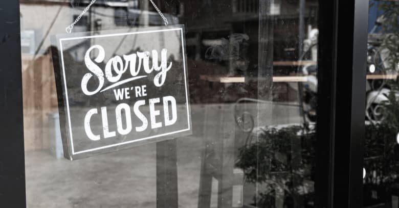 A 'Sorry We're Closed' sign is visible through the glass doors of a business