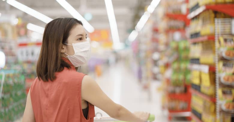 A woman is wearing a medical mask while she shops for groceries