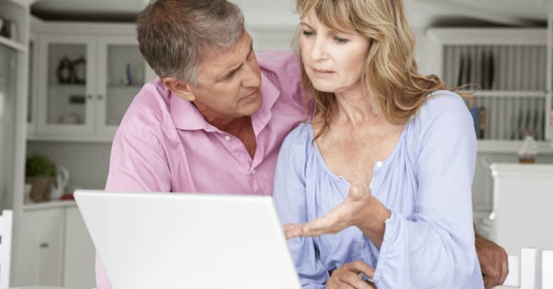 An older couple sits at a computer and discusses their finances in a serious manner