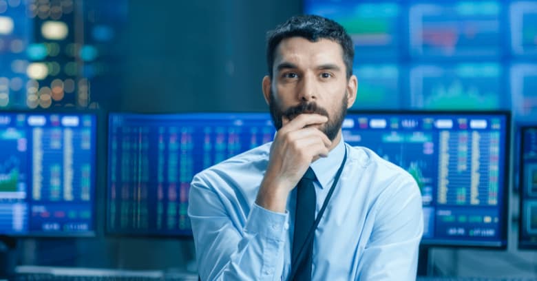 a stock trader is sitting at a desk in front of a computer in a stock exchange