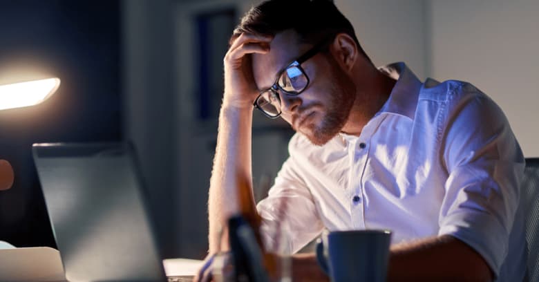 a man sits at a computer and looks concerned