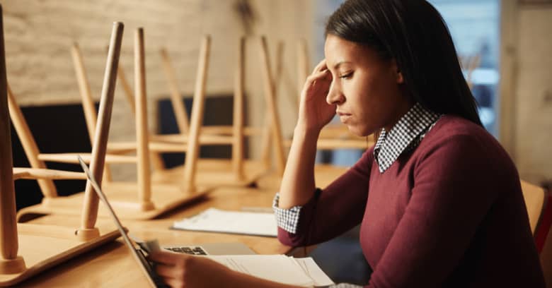 A restaurant owner works on her finances with a worried look on her face as she considers the ramifications of her business being closed during the coronavirus