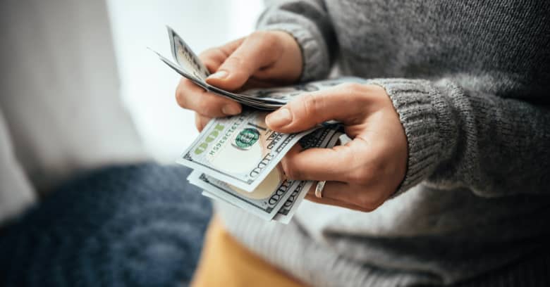 a set of hands holding cash is visible