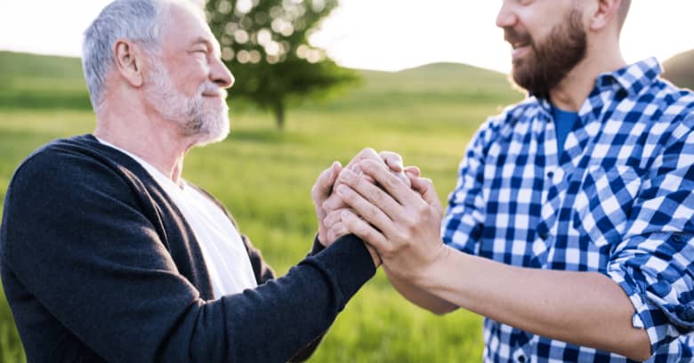 A father and son smiling at each other and grasping hands