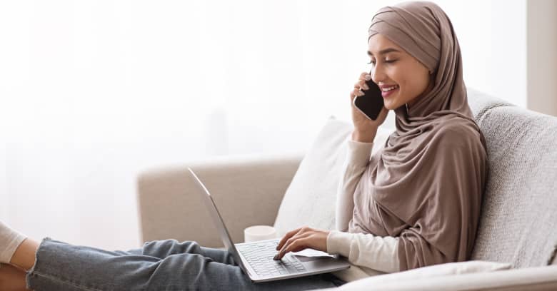 A woman talks on her phone while looking on her computer