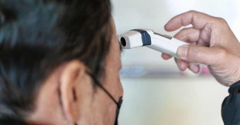 A man's temperature is checked as part of a screening process for coronavirus