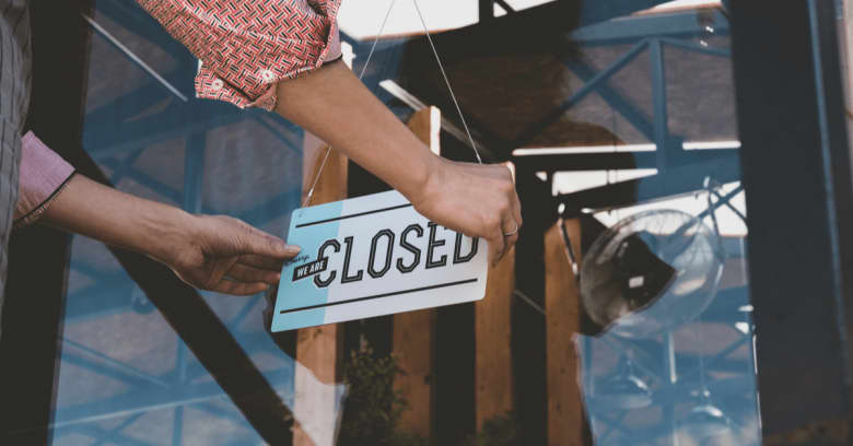 A business owner puts a 'closed' sign on the front door of her place of business