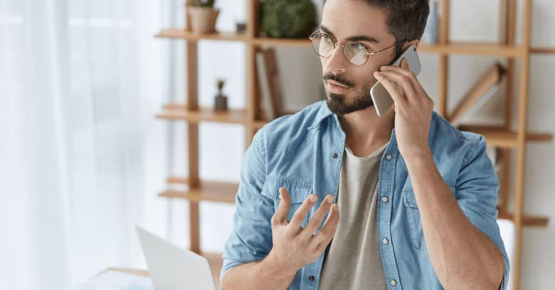 a small business owner talks on the phone with a serious expression on his face