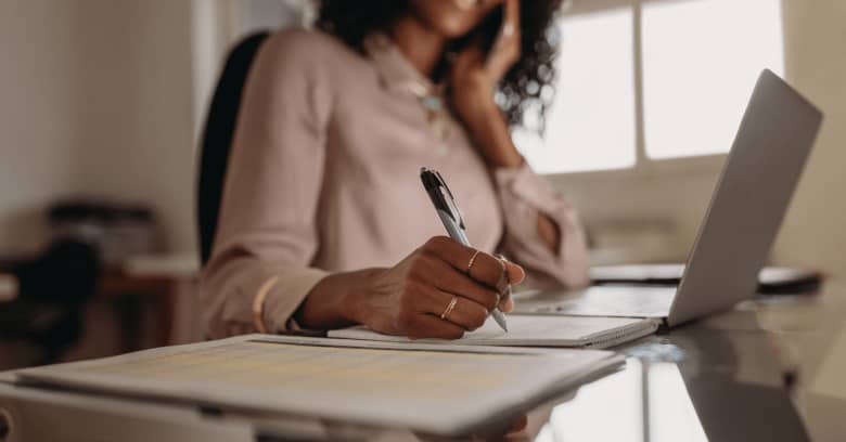 a business owner researches business insurance on her computer and takes notes