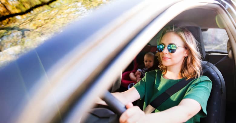 woman driving a car with a baby in the backseat