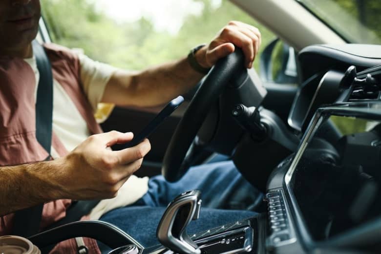 Man driving looking at cell phone