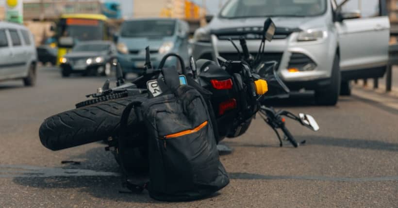 A motorcycle lies in the middle of the road after a collision with another vehicle.