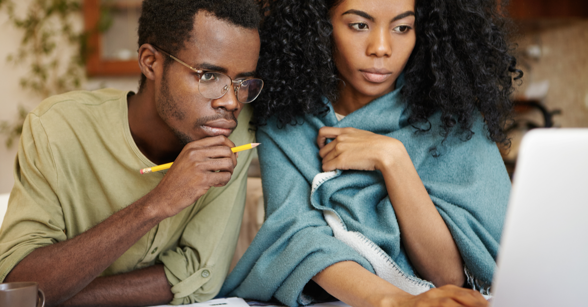 a couple looks at their tax returns on the computer with concern