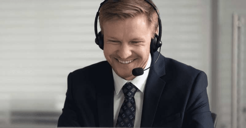 A man wears headphones with a microphone while looking at the computer.