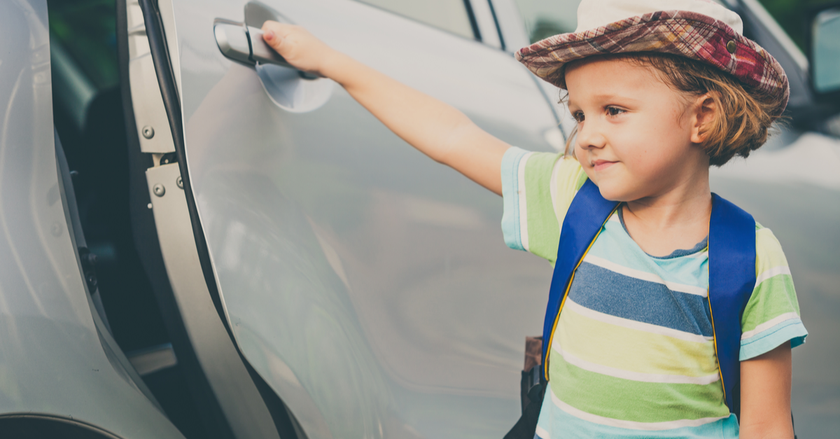 A young child opens the door to a car as he prepares to get inside