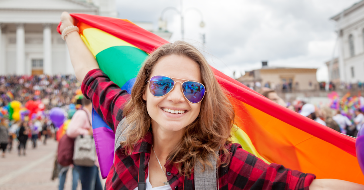 A woman waves a big flag during a pride celebration