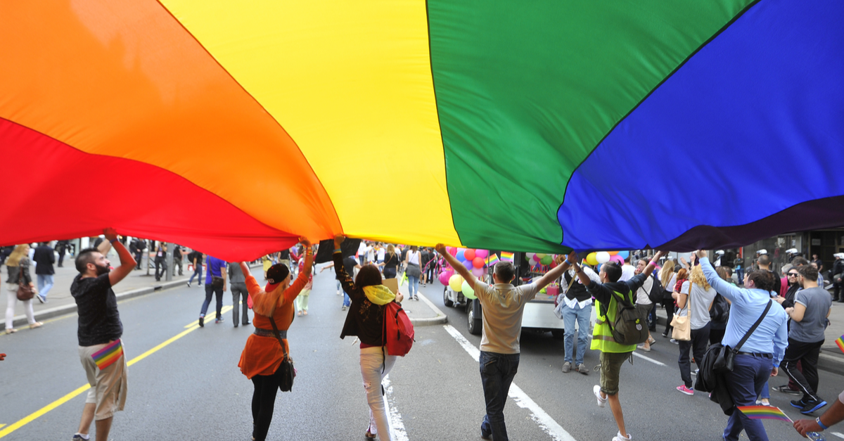 A group of people hold up a pride flag during a parade