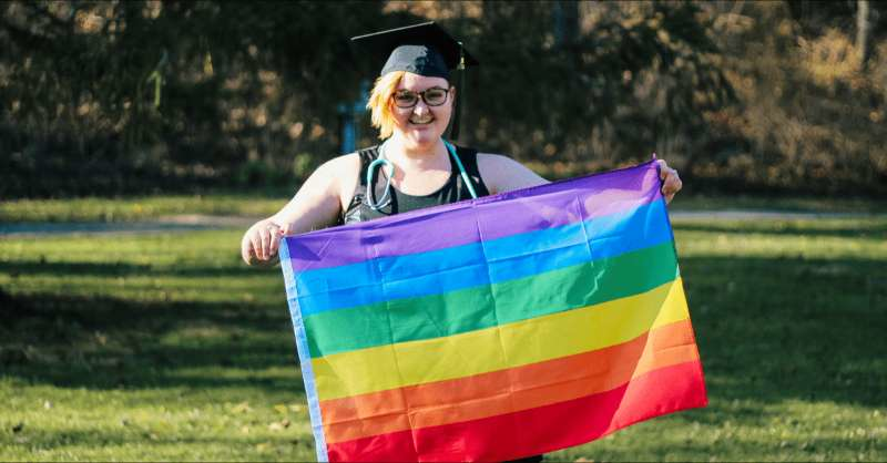 a woman holds an LGBTQ+ rainbow flag