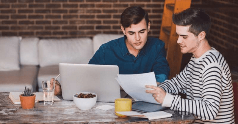 A gay married couple sits at a table as they discuss their taxes