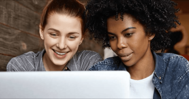 two women look at a computer together.