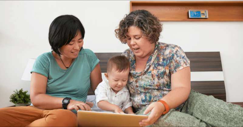 two moms play with their toddler son