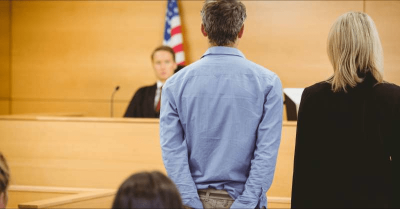 A handcuffed man faces a judge in court