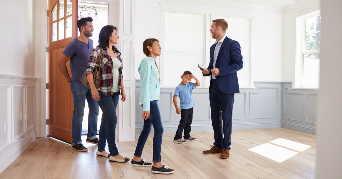 A family is shown a new home by their real estate agent