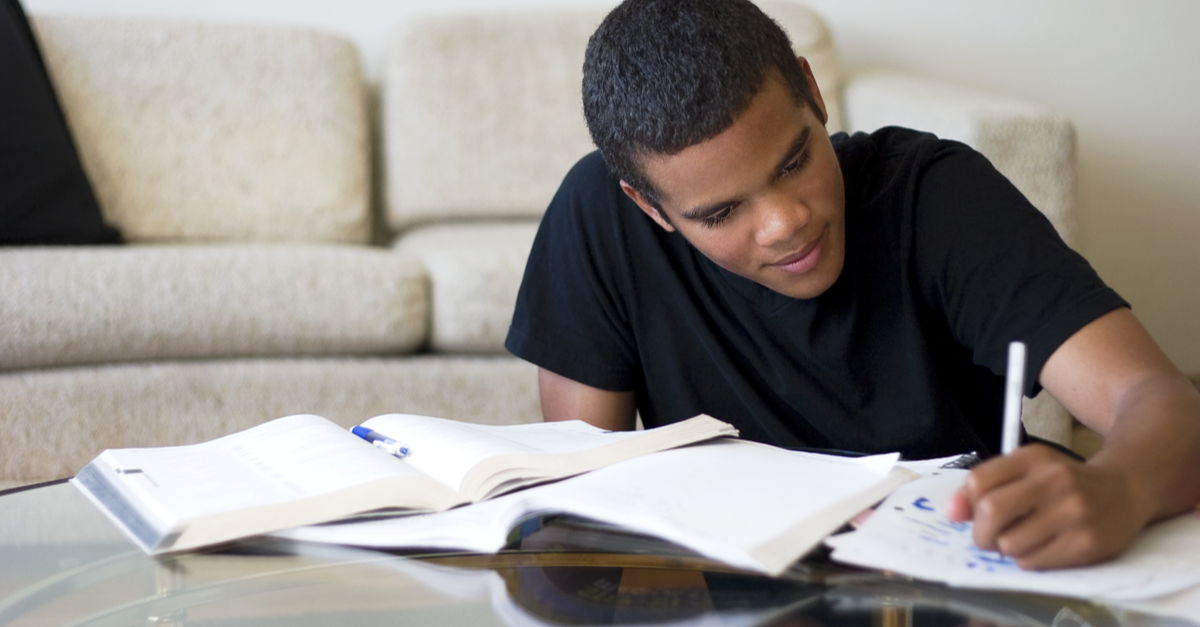 A young male college student does homework in his apartment